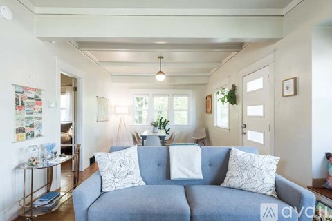 A living room with a grey couch and a glass table.