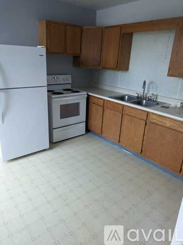 A kitchen with white appliances and wooden cabinets.