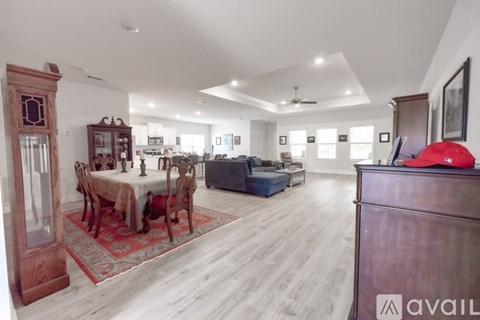 A spacious living room with a dining table set up with chairs and a couch in the background.