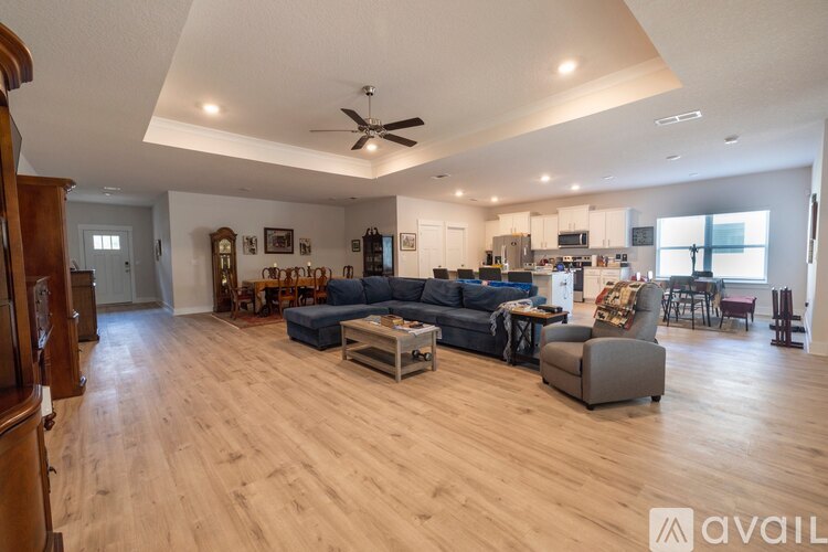 A spacious living room with wooden flooring and furniture.