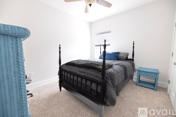 A bedroom with a black four-poster bed and a blue chair.