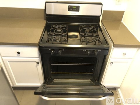 A modern black and silver oven with the door open is in a kitchen.