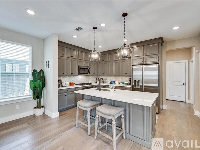 A modern kitchen with a large island and bar stools.