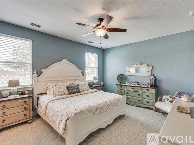 A bedroom with a large bed, a dresser, and a ceiling fan.