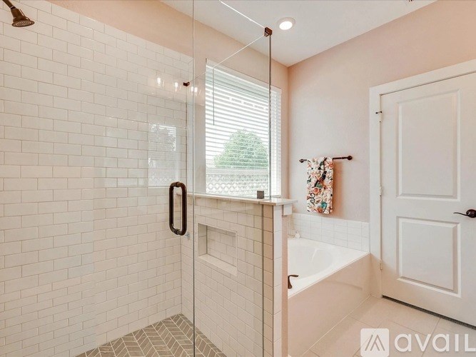 A white tiled bathroom with a glass shower door and a white bathtub.