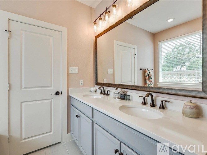 A bathroom with a white door, a large mirror, and a window.