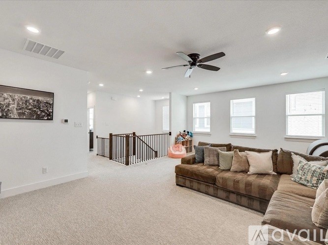 A spacious living room with a brown sofa and a ceiling fan.