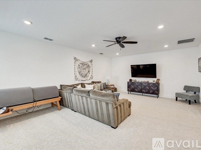 A living room with a grey sofa, a brown couch, and a television on the wall.