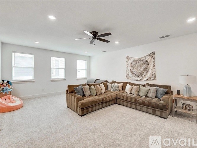 A living room with a large sectional sofa and a ceiling fan.