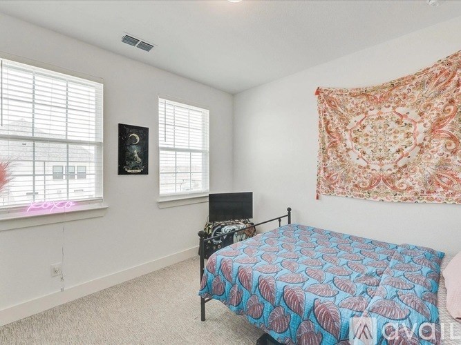 A bedroom with a bed, a chair, and a window with blinds.