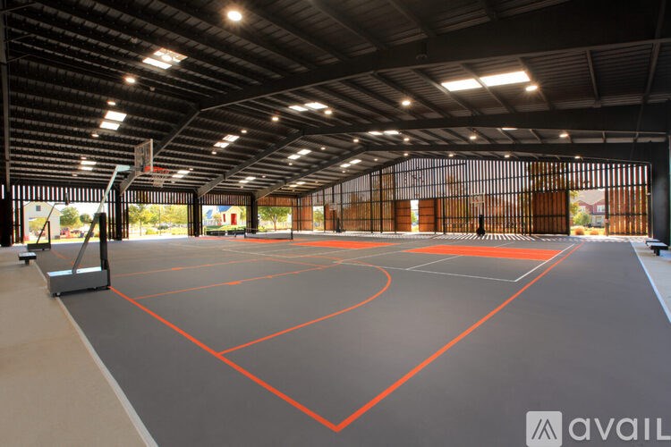 A basketball court with a black and orange surface is shown inside a large indoor facility.