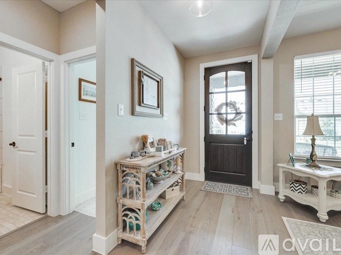 A hallway with a white door, a black door, and a white bench with decorative items on it.
