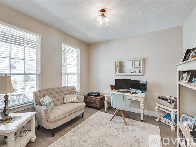 A living room with a couch, a desk, and a lamp.