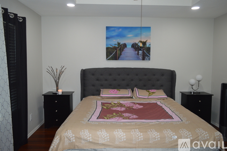 A bedroom with a large bed and a painting of a bridge on the wall.