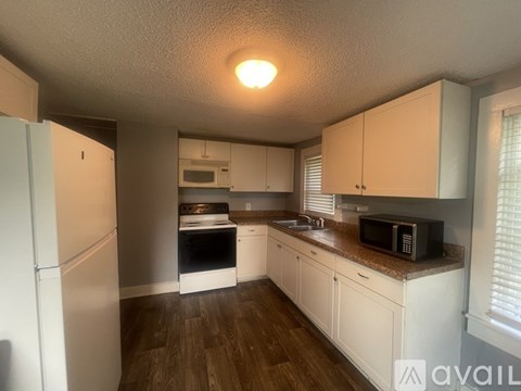 A kitchen with white cabinets and a refrigerator.