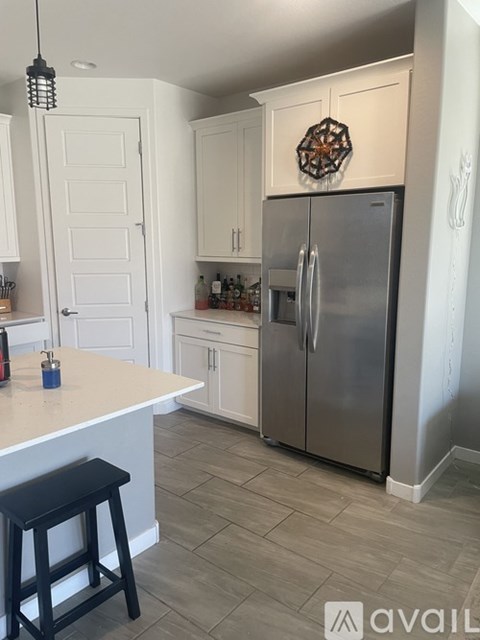 A kitchen with a white counter and a black stool.