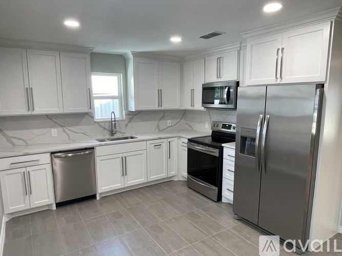 A kitchen with white cabinets and a stainless steel refrigerator.