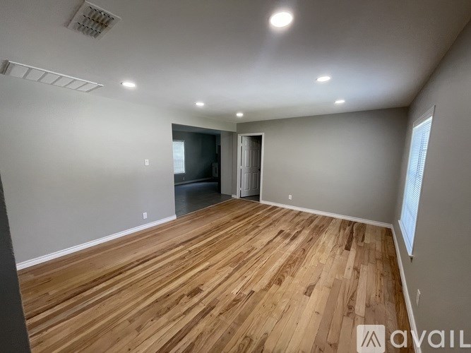 A room with wooden flooring and a doorway leading to another room.