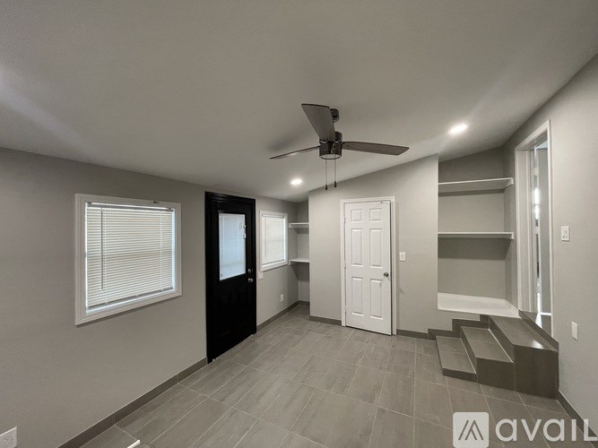 A spacious room with a ceiling fan and a window with blinds.