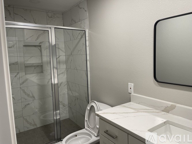 A bathroom with a toilet, sink, and mirror.