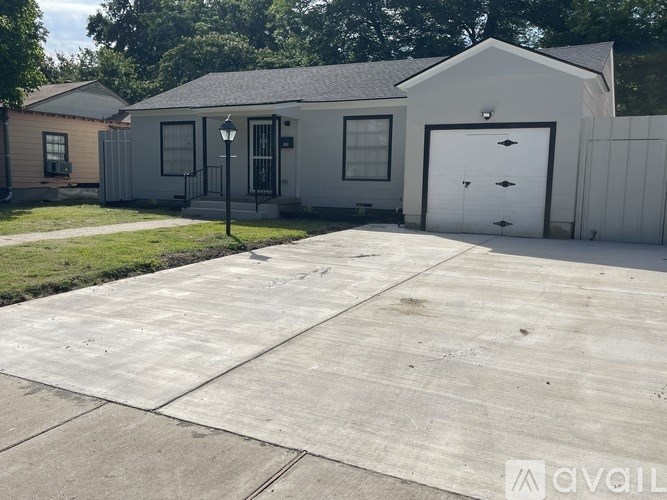A white house with a black door and a grey garage door.