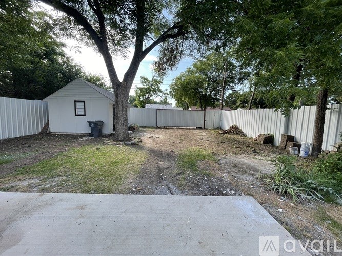 A backyard with a shed, fence, and a tree.