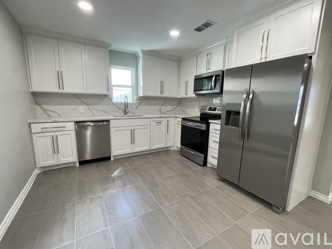 A kitchen with white cabinets and a grey floor.