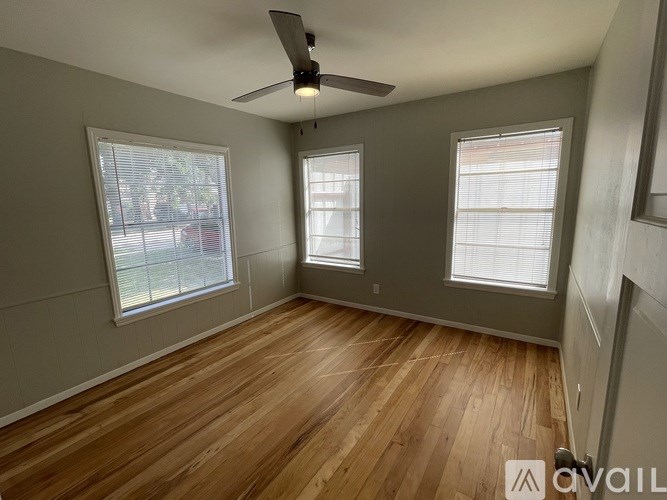 A room with wooden floors and two windows.
