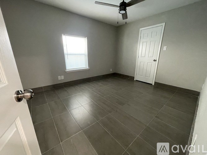 A room with a ceiling fan, a door, and a window.