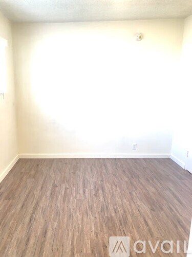 A room with wooden flooring and a wall socket.