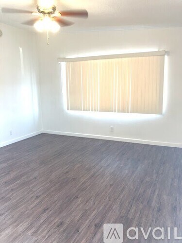 A room with a ceiling fan and a window with blinds.