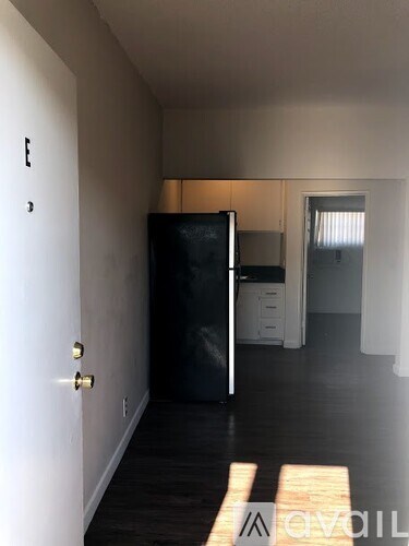 A black refrigerator sits in a kitchen with white cabinets and a white door.
