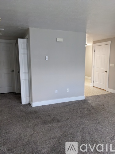 A room with a carpeted floor and a door on the right side.