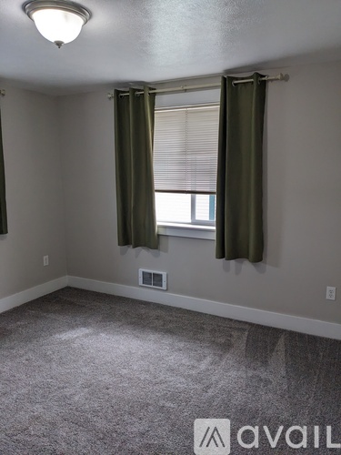A room with a window covered by green curtains.