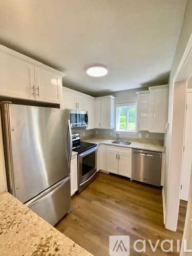 A kitchen with a stainless steel refrigerator and white cabinets.