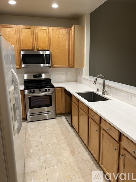 A kitchen with wooden cabinets and a stainless steel refrigerator.