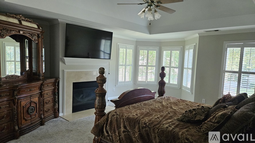 A bedroom with a large bed, a fireplace, and a television.