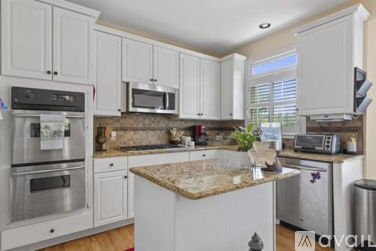 A kitchen with white cabinets and a granite countertop.