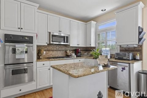 A kitchen with white cabinets and a granite countertop.