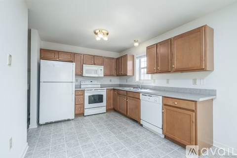 A kitchen with white appliances and brown cabinets.