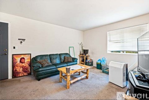 A living room with a green couch, a wooden coffee table, and a painting of a woman.