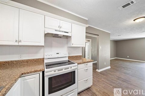 A kitchen with white cabinets and a white stove top oven.