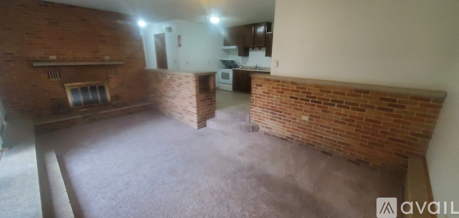 A room with wooden floors and a black refrigerator.