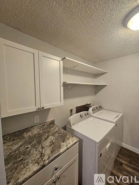 A kitchen with white cabinets and a granite countertop.