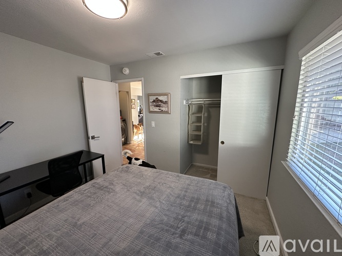 A bedroom with a bed, dresser, and a window with blinds.