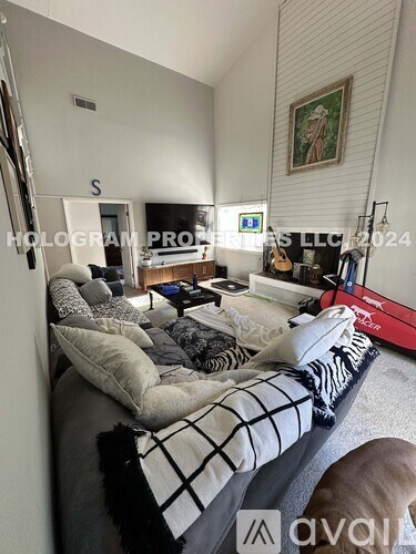 A living room with a couch, a coffee table, a guitar, and a painting on the wall.