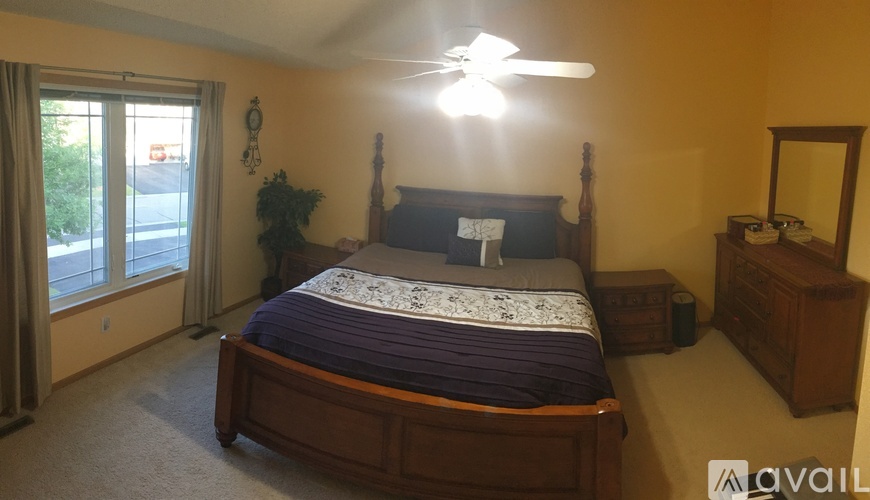 A bedroom with a bed, dresser, mirror, and a ceiling fan.