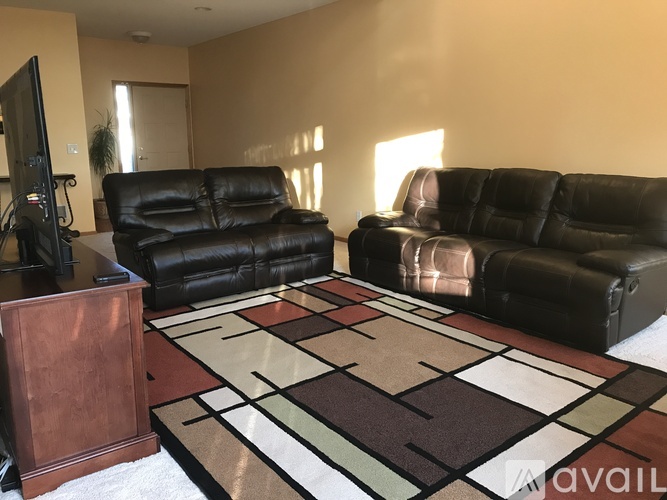 A living room with a black leather couch and a wooden speaker.