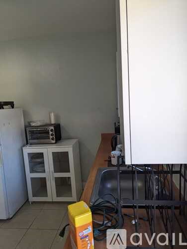 A kitchen with a white fridge, a sink, and a cabinet with a radio on top.