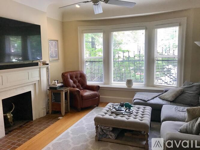 A living room with a fireplace, a red leather chair, a grey couch, and a television.